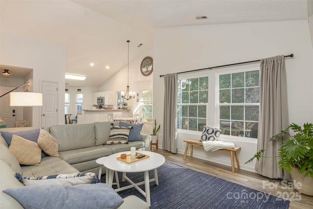 living room with recessed lighting, visible vents, an inviting chandelier, wood finished floors, and high vaulted ceiling