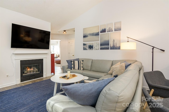 living area with lofted ceiling, wood finished floors, and a glass covered fireplace