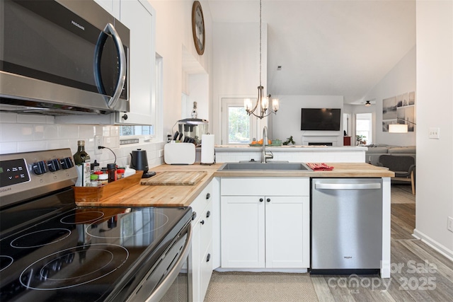 kitchen featuring stainless steel appliances, butcher block counters, white cabinetry, and a sink