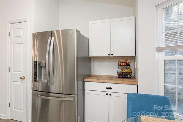 kitchen featuring butcher block countertops, white cabinetry, vaulted ceiling, tasteful backsplash, and stainless steel fridge