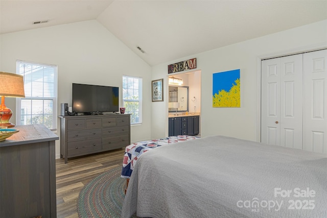 bedroom featuring lofted ceiling, a closet, wood finished floors, and visible vents