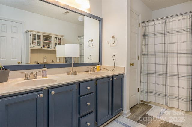 bathroom with double vanity, wood finished floors, a sink, and a shower with curtain