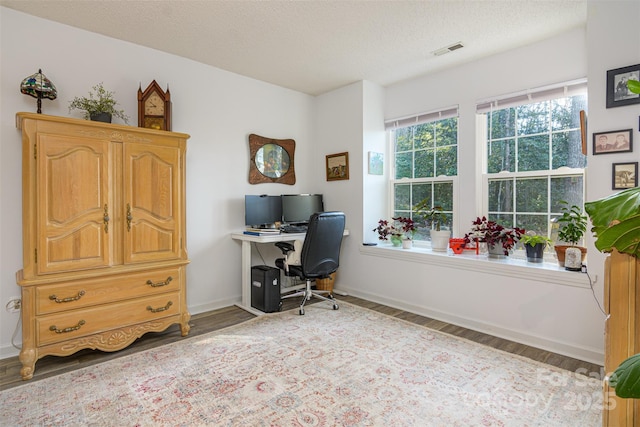 home office with baseboards, visible vents, and wood finished floors