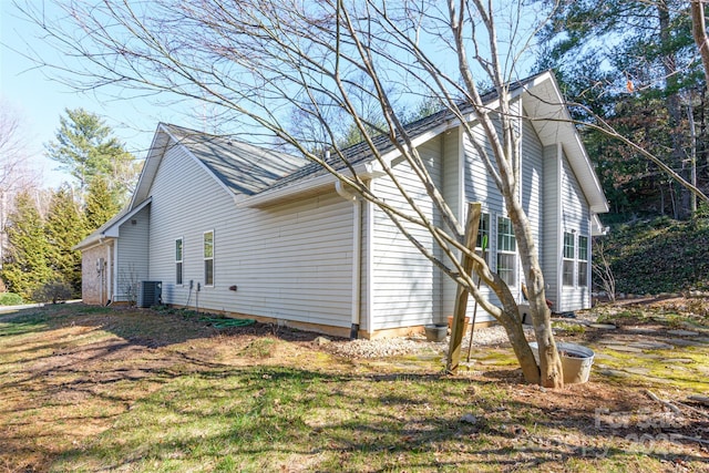 view of side of property with central AC unit and a lawn