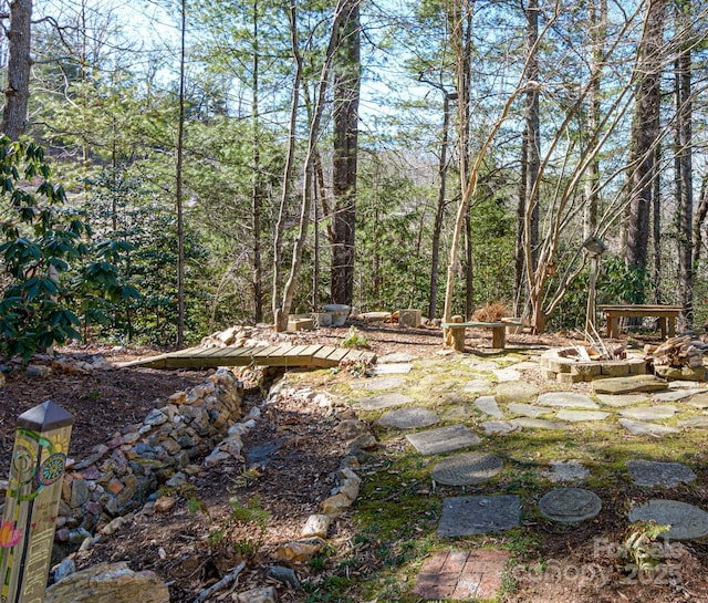 view of yard with a forest view and an outdoor fire pit