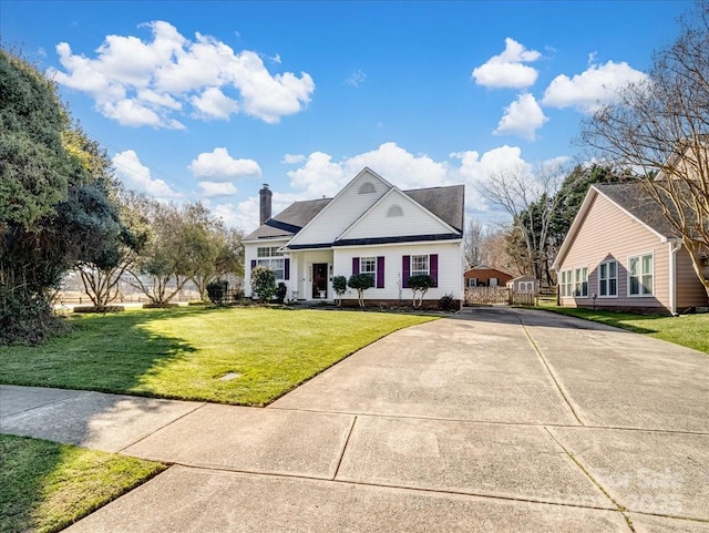 view of front facade featuring driveway, a front lawn, and a chimney