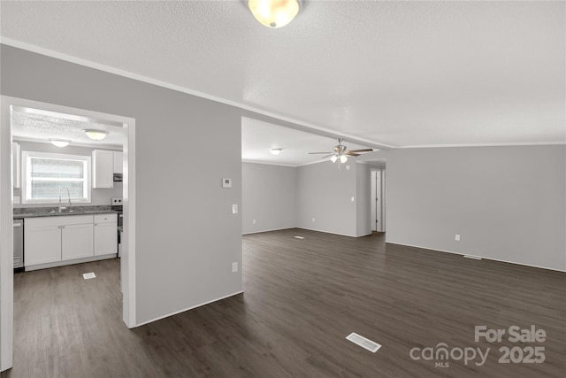 unfurnished living room with visible vents, dark wood-type flooring, a ceiling fan, a sink, and a textured ceiling