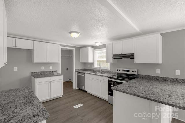 kitchen with appliances with stainless steel finishes, wood finished floors, under cabinet range hood, white cabinetry, and a sink