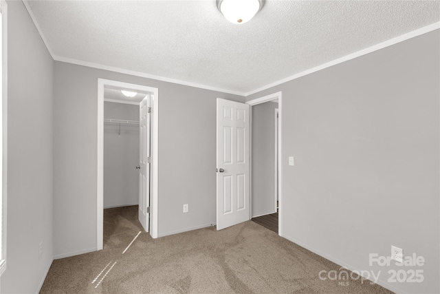 unfurnished bedroom with ornamental molding, a closet, carpet flooring, and a spacious closet