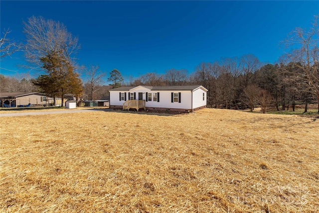 view of front of house featuring a front yard, crawl space, an outdoor structure, and a shed