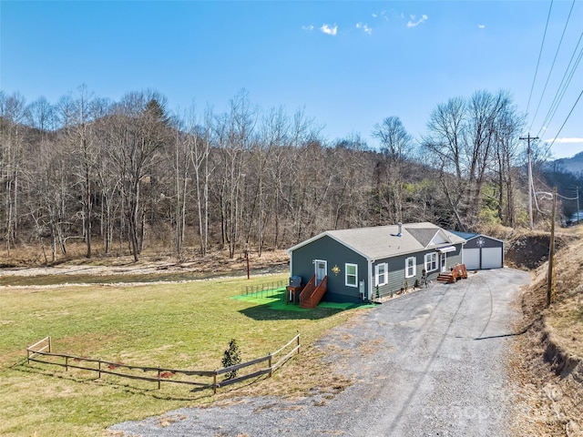 view of front facade with driveway, a front yard, fence, and an outbuilding