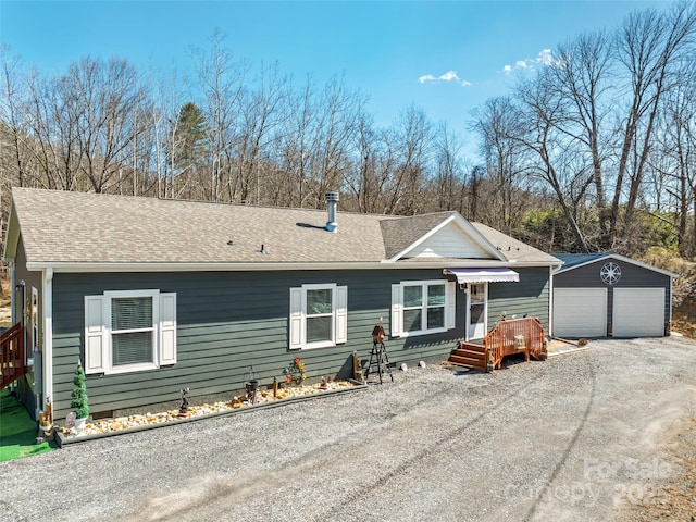 view of front facade with an outbuilding, a shingled roof, and a detached garage