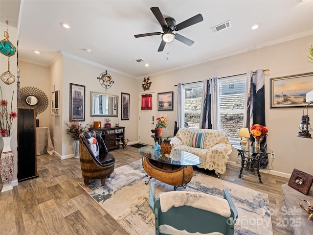 living room featuring baseboards, crown molding, visible vents, and wood finished floors