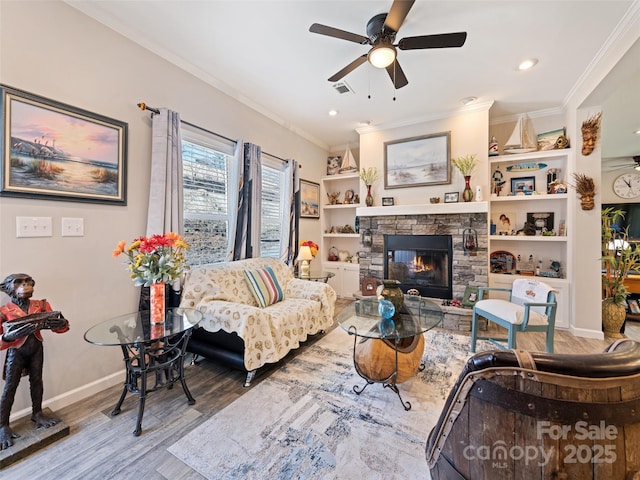 living room with crown molding, visible vents, a stone fireplace, wood finished floors, and baseboards