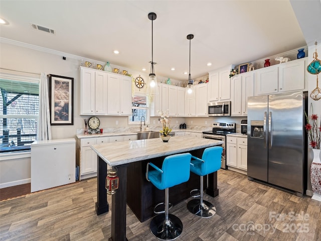 kitchen featuring appliances with stainless steel finishes, visible vents, crown molding, and wood finished floors