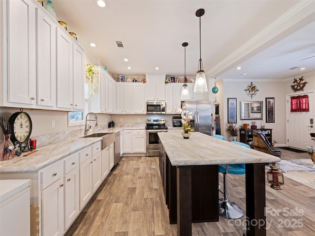 kitchen featuring a sink, visible vents, light wood-style floors, ornamental molding, and appliances with stainless steel finishes