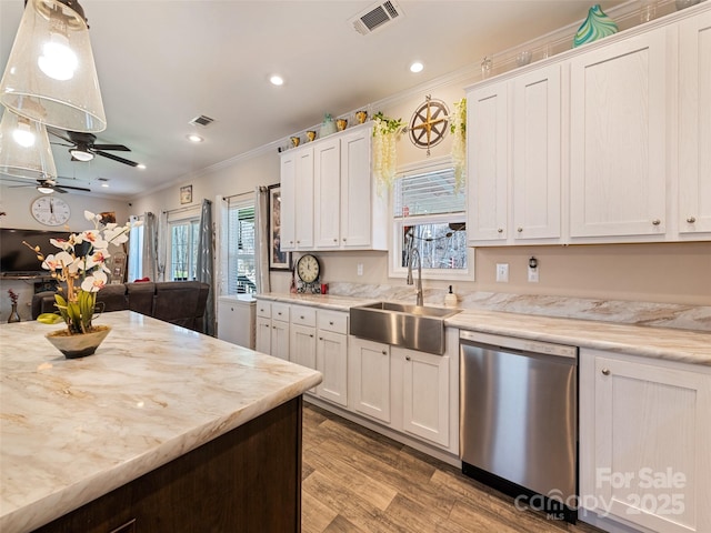 kitchen featuring visible vents, stainless steel dishwasher, crown molding, light wood-style floors, and a sink