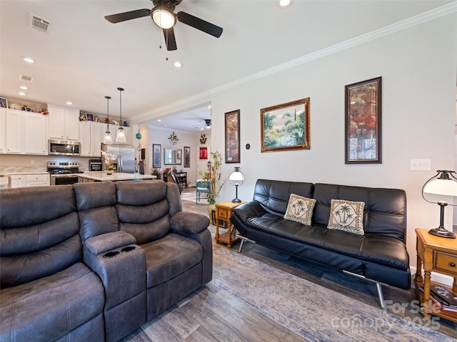 living area with recessed lighting, wood finished floors, visible vents, and crown molding