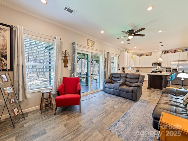 living area featuring crown molding, recessed lighting, visible vents, light wood-type flooring, and baseboards