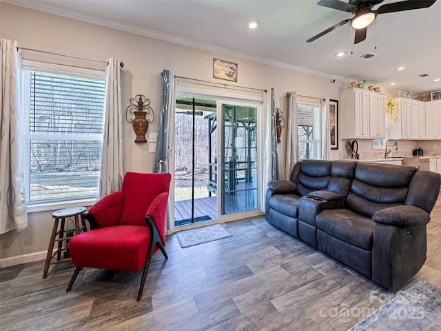 living room featuring baseboards, light wood finished floors, visible vents, and crown molding