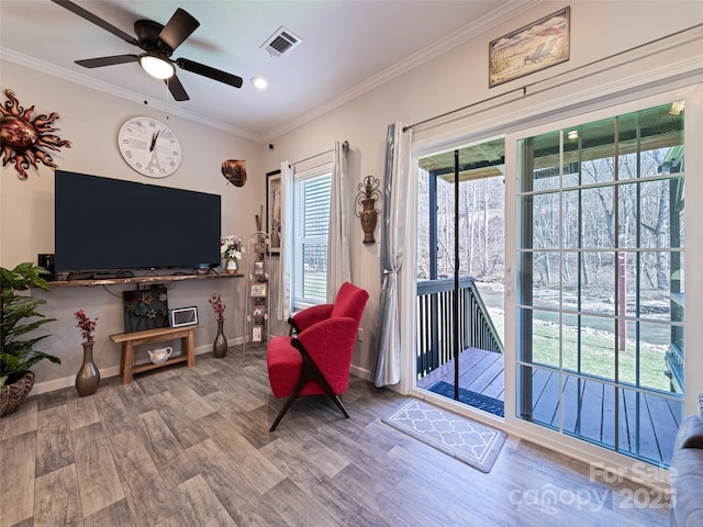 sitting room featuring baseboards, crown molding, visible vents, and wood finished floors