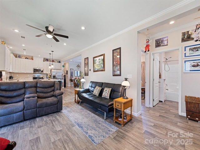 living area with baseboards, visible vents, ornamental molding, light wood-type flooring, and recessed lighting