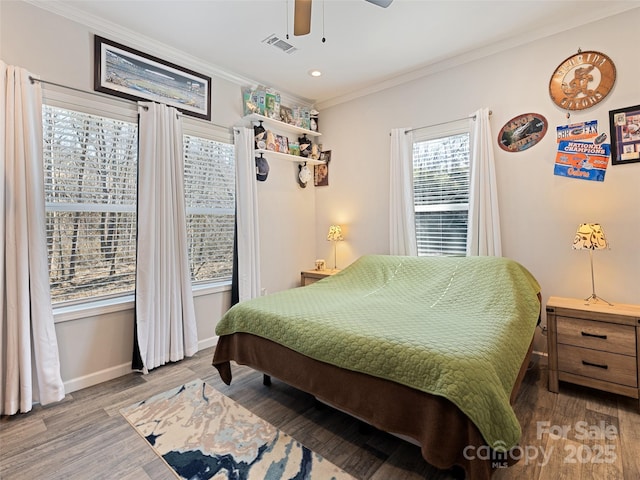 bedroom featuring ornamental molding, wood finished floors, visible vents, and baseboards