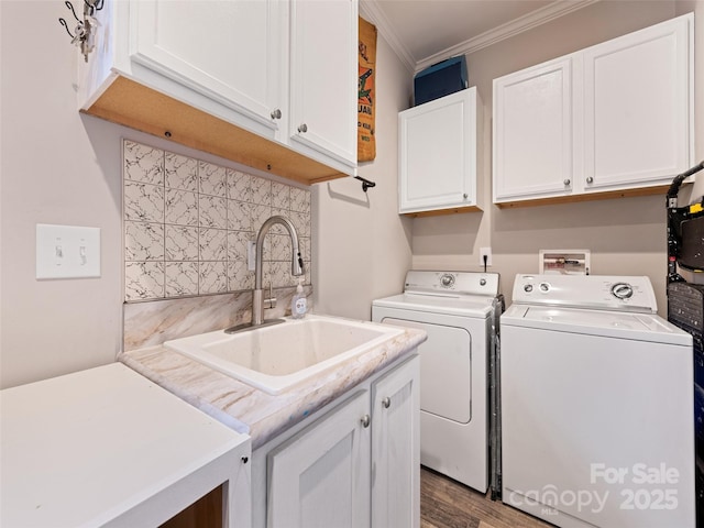 washroom featuring cabinet space, wood finished floors, crown molding, separate washer and dryer, and a sink