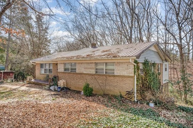 view of side of home featuring metal roof and brick siding