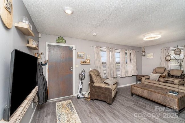 living room featuring a textured ceiling, wood finished floors, and baseboards