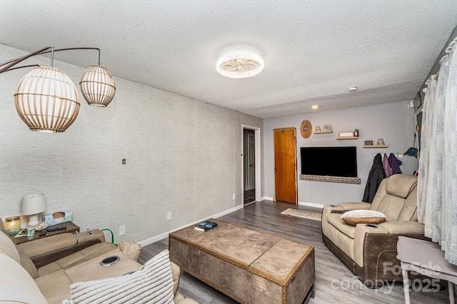 living area featuring a textured ceiling, baseboards, and wood finished floors