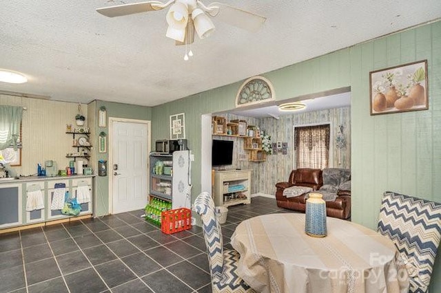 tiled dining space featuring a textured ceiling and ceiling fan