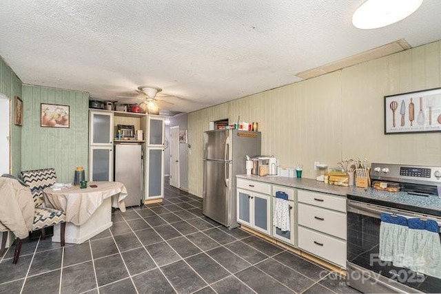 kitchen with a textured ceiling, dark tile patterned flooring, appliances with stainless steel finishes, and a ceiling fan