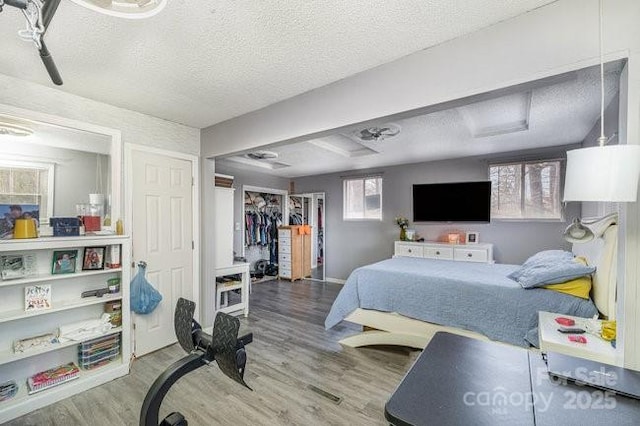 bedroom with attic access, a textured ceiling, a closet, and wood finished floors