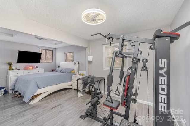 bedroom featuring a textured ceiling, baseboards, and wood finished floors