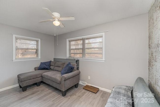 living room with ceiling fan, light wood finished floors, plenty of natural light, and baseboards