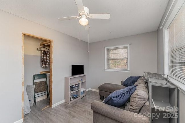 living area featuring ceiling fan, baseboards, and wood finished floors