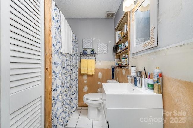 bathroom with visible vents, toilet, vanity, a textured ceiling, and tile patterned flooring