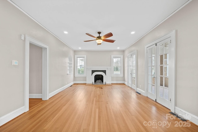 unfurnished living room with ornamental molding, light wood-type flooring, a fireplace, and baseboards