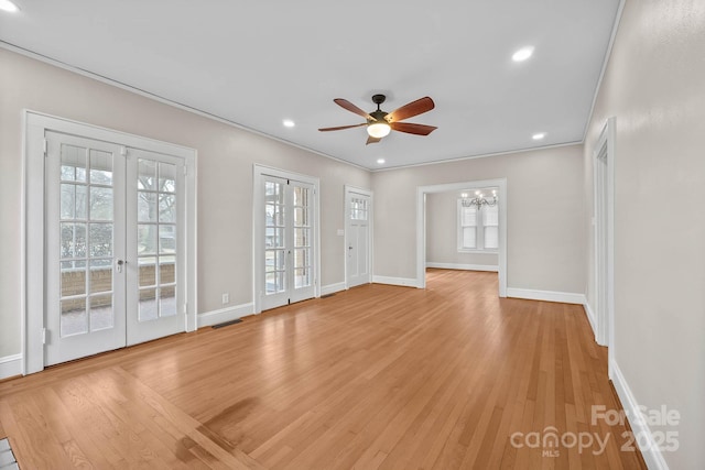 empty room with light wood-style flooring, ceiling fan with notable chandelier, visible vents, and french doors