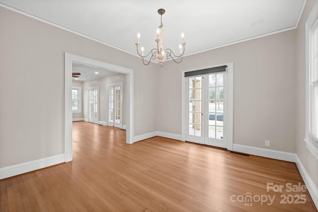empty room with crown molding, baseboards, visible vents, and light wood-style floors