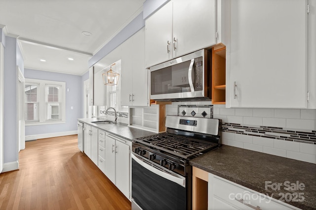 kitchen featuring appliances with stainless steel finishes, a sink, white cabinets, and decorative backsplash