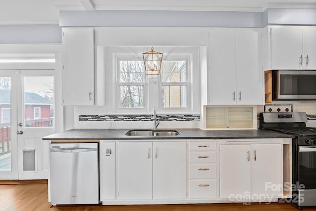 kitchen with stainless steel appliances, dark countertops, white cabinets, and a sink