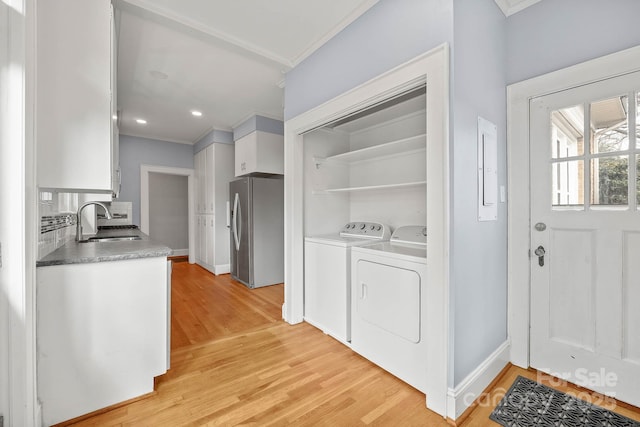 kitchen with a sink, white cabinetry, light wood-type flooring, stainless steel refrigerator with ice dispenser, and washer and clothes dryer