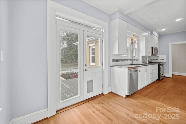 kitchen featuring white cabinets, appliances with stainless steel finishes, ornamental molding, light wood-type flooring, and backsplash