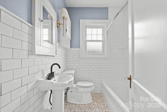 full bath with toilet, tile walls, and bathing tub / shower combination
