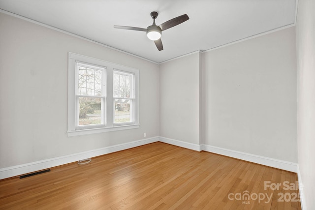 unfurnished room featuring visible vents, crown molding, baseboards, and wood finished floors