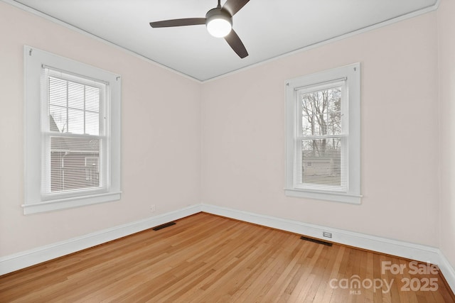 spare room with visible vents, plenty of natural light, and hardwood / wood-style floors