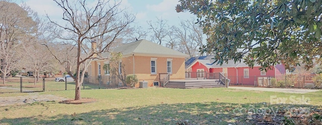 exterior space with central AC unit, a yard, fence, a wooden deck, and brick siding