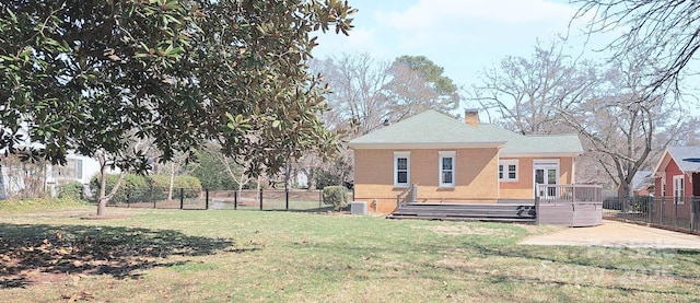 rear view of house featuring a deck, brick siding, fence, a yard, and a chimney